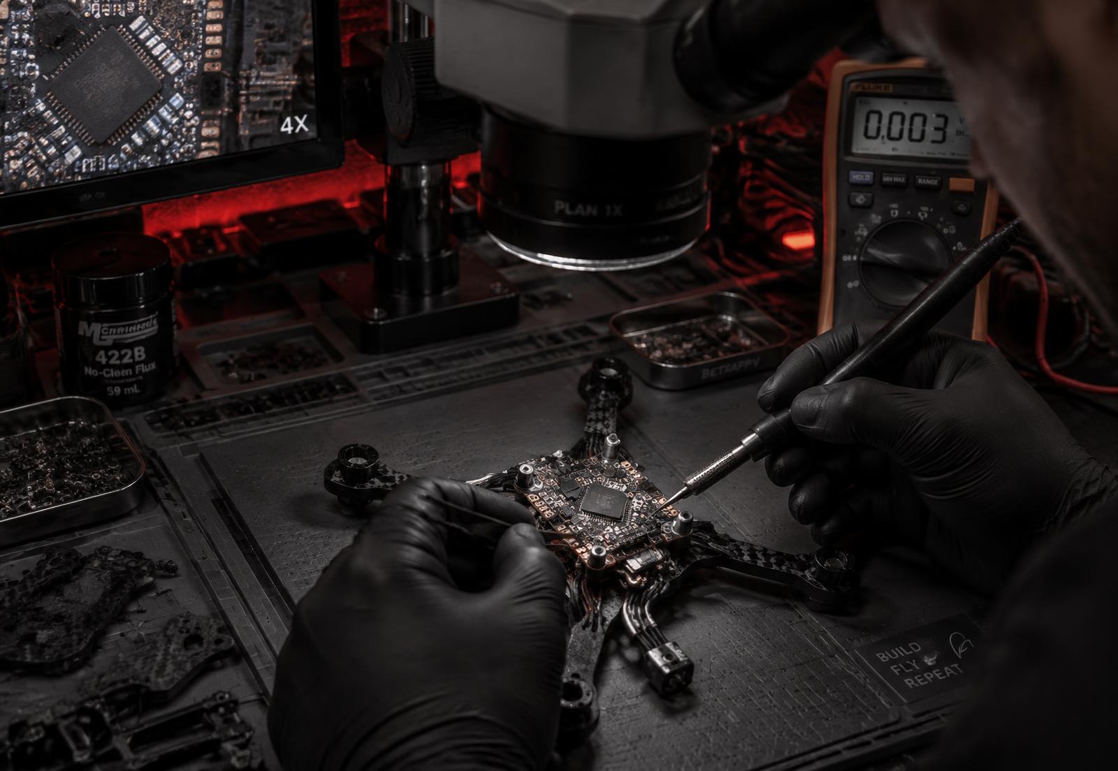 Técnico soldando placa de drone sob microscópio em bancada profissional